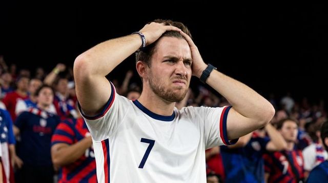 Tense soccer fan holding head wearing number 7 jersey in stadium crowd