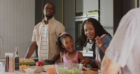 Diverse family cooking together at modern kitchen island sharing joyful meal prep moment