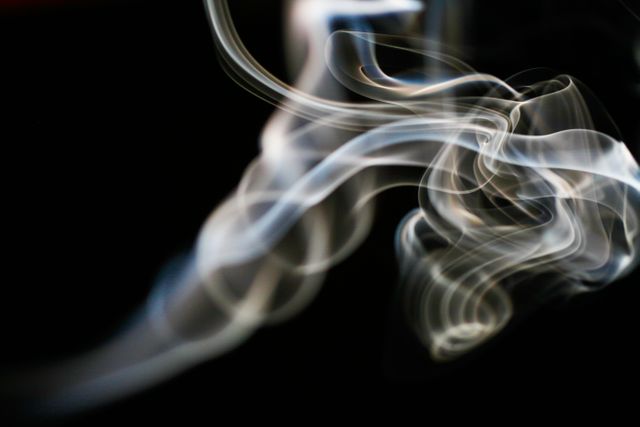 Flowing smoke effect on black background creates a mystical and ethereal feel, suitable for backgrounds, design concepts, and artistic visuals. The swirling patterns add a sense of movement and intrigue, making it perfect for use in digital art, graphic design projects, and promotional materials focused on elegance and mystery.