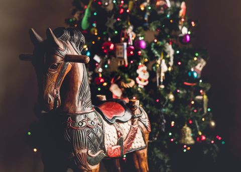 Traditional wooden toy christmas horse with christmas tree in background