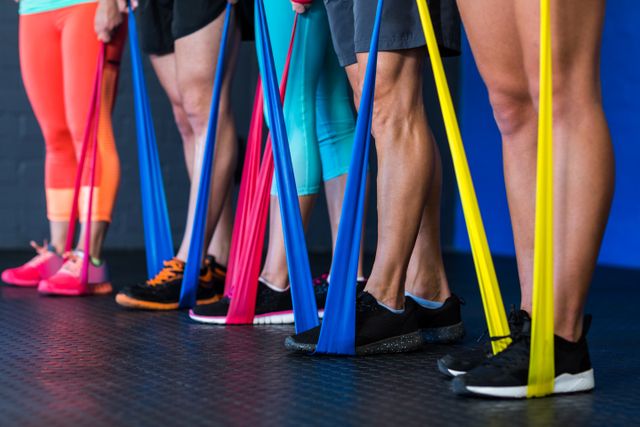 Low section of athletes exercising with resistance band in gym