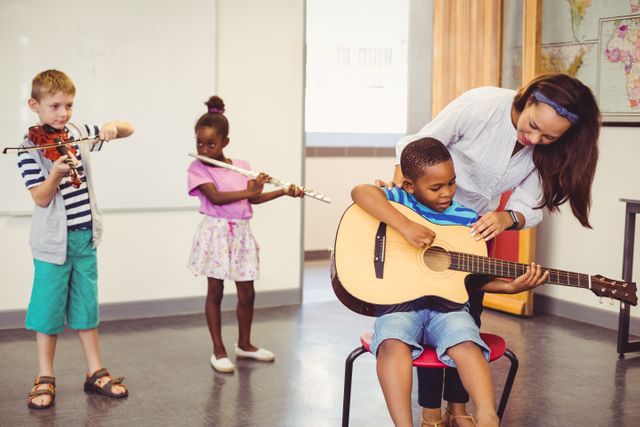 Teacher assisting a kids to play a musical instrument in classroom at school