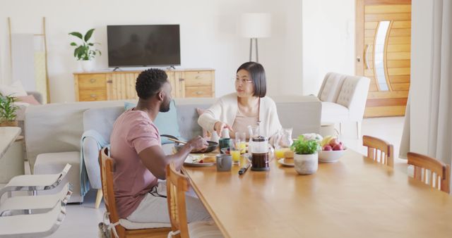 Happy diverse couple sitting at table and having breakfast - Download Free Stock Photos Pikwizard.com