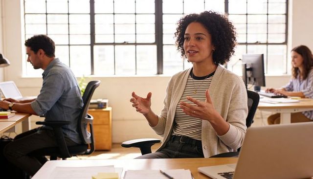 Professional woman leading collaborative discussion in bright open-plan office workspace
