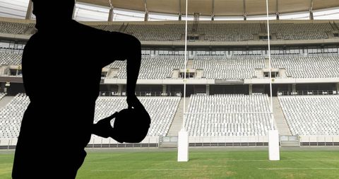 Silhouette of Rugby Player Holding Ball at Empty Stadium