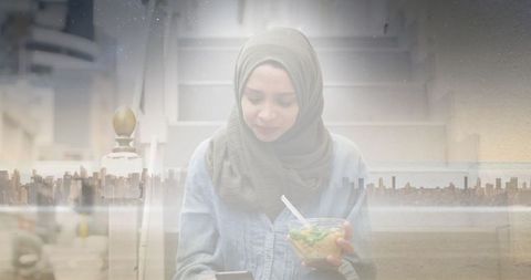 Urban lifestyle: woman in hijab eating salad with cityscape overlay