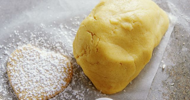 Heart shaped cookie dough placed on parchment paper dusted with powdered sugar, showcasing homemade baking preparations. Ideal for blogs about baking, dessert recipes, Valentine’s Day themes, and food magazines.