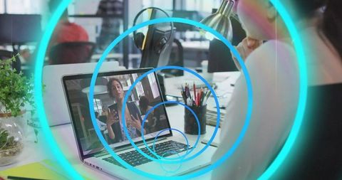 Remote team collaborating via video call on laptop in open office with augmented overlay