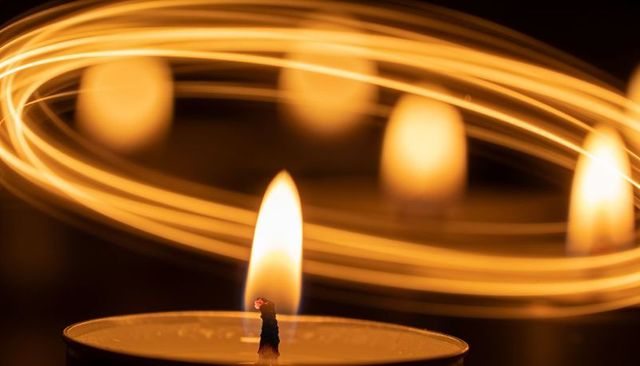 Golden tealight flame with circular light trails, long exposure close-up for mood lighting