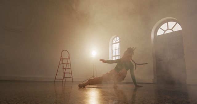 This stock photo captures a dancer performing a contemporary dance in a foggy room with dramatic lighting. The hazy atmosphere and spotlight create a sense of mystery and highlight the dancer’s movements. Use this image for articles or content related to dance, performing arts, creativity, dance studios, or expressive movement.