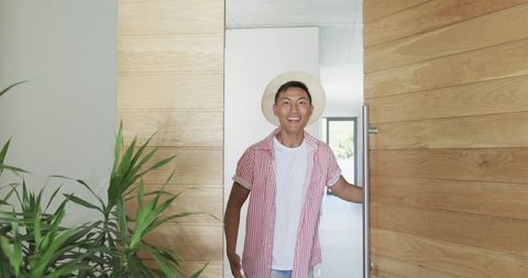 Smiling young man welcoming guests to modern home