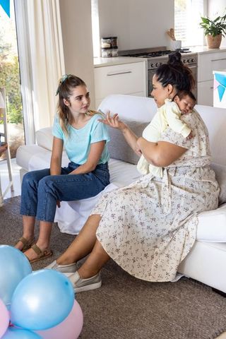 Mother and Daughter Bonding with Newborn at Home
