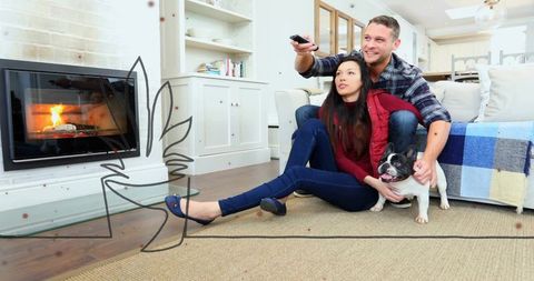 Couple relaxing at home with french bulldog near cozy fireplace