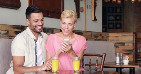 Happy Couple Enjoying Smartphone Time at Cozy Cafe
