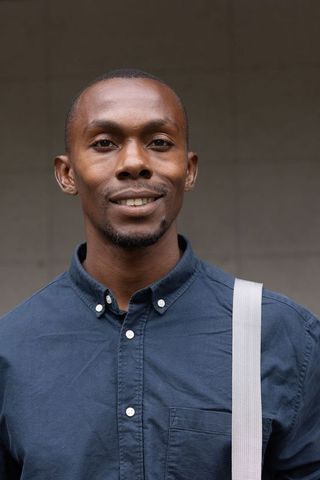 Confident urban professional wearing navy button-down with shoulder strap portrait