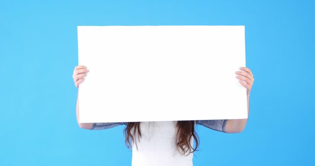 Person Holding Blank White Poster Board Against Blue Background - Download Free Stock Images Pikwizard.com