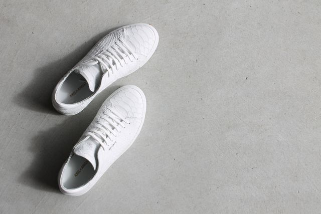 White sneakers placed on a minimalist concrete background, showcasing a clean and modern aesthetic. Use for fashion marketing, product presentations, or lifestyle blogs highlighting casual footwear trends.