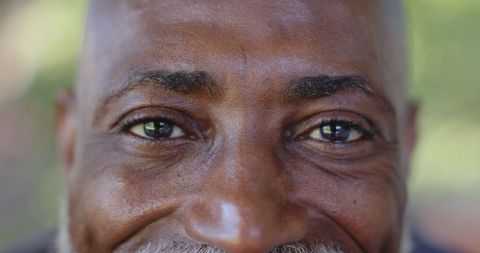 Closeup portrait of smiling senior african man gazing with warm eyes and textured skin