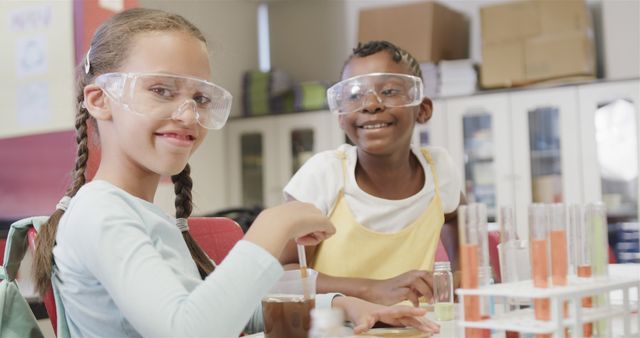 Portrait of happy diverse schoolgirls doing expeiments during science lesson at school. Education, learning, science, inclusivity and school, unaltered.