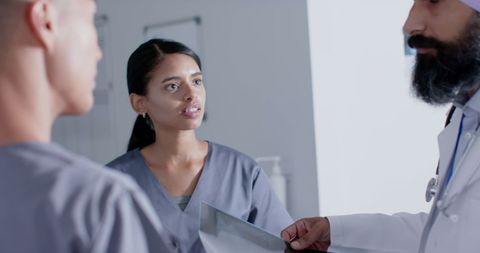 Focused Doctors Discussing X-Ray in Busy Hospital Corridor