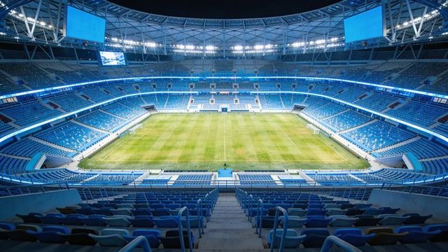 Panoramic empty modern soccer stadium interior with illuminated blue seats and green pitch