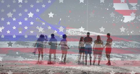 Group standing facing ocean on sandy beach with american flag overlay for patriotic summer