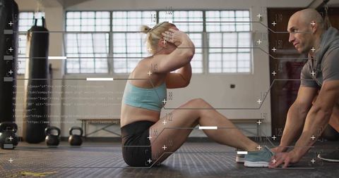 Woman performing seated crunches with trainer holding feet and digital fitness hud overlay