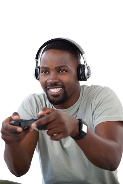 Young man enjoying video game with headphones, holding controller, smiling. Ideal for use in articles about gaming, technology, leisure activities, or mental health benefits of gaming.