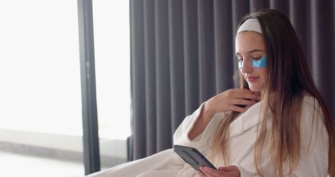 Relaxed woman enjoying selfcare at home with headband and eye patches