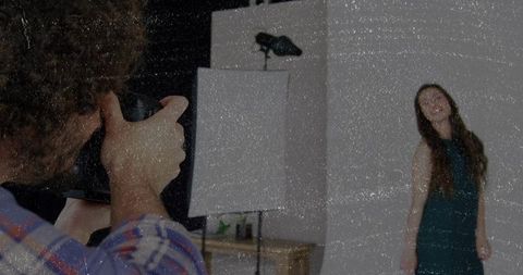 Studio photographer capturing model posing with backdrop contrast