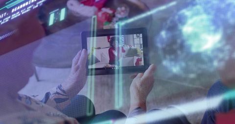 Senior couple watching tablet video call with festive red-sweater caller and holographic ui