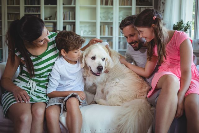 Family sitting on sofa with pet dog in living room at home