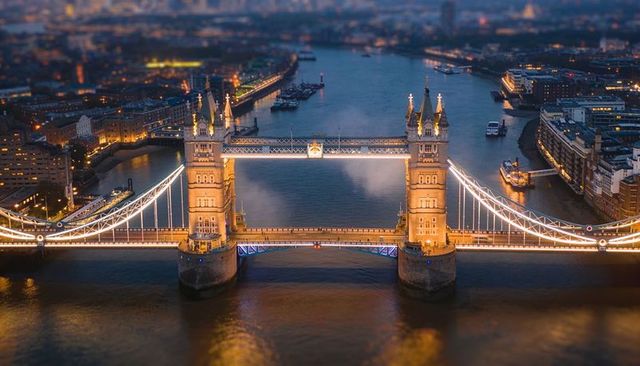 Glowing tower bridge at dusk with illuminated turrets and river reflections