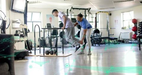 Trainer assisting client on parallel bars during assisted dip for strength and balance