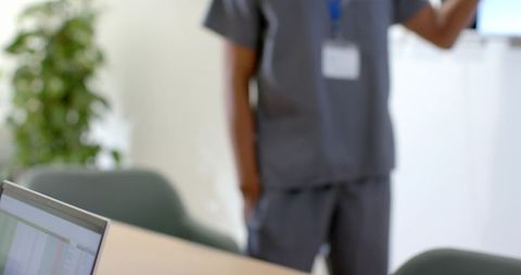 African american clinician presenting data in clinic wearing scrubs and lanyard