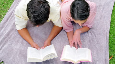 Couple Relaxing on Blanket Enjoying Books in Park