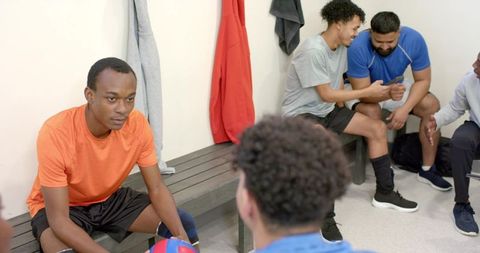 Prematch volleyball team in locker room, diverse male teammates preparing and focusing
