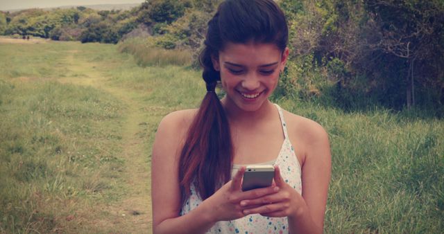 Young Woman Outdoors Smiling at Smartphone - Download Free Stock Images Pikwizard.com