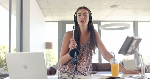 Confident Teen Girl Podcasting in Modern Workplace with Laptop and Headphones