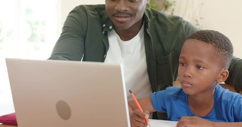 African american father helping son with homework on laptop, remote learning and study