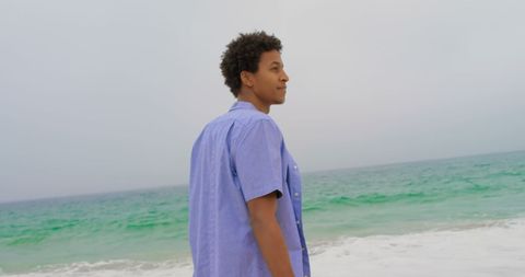 Man peacefully enjoys coastal breeze while gazing at the ocean, conveying a serene sense of freedom. Perfect for themes of relaxation, outdoor lifestyle, or travel inspiration. Ideal for use in marketing materials for beach vacations, relaxation techniques, and wellness retreats.