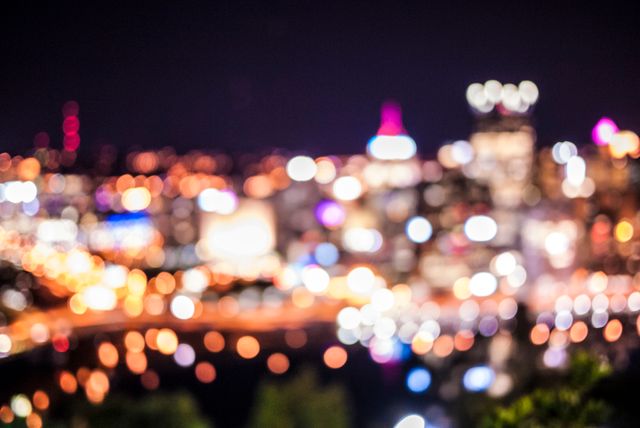 Blurry city lights with vibrant bokeh effects create an abstract and colorful urban night scene. Ideal for backgrounds, decorative art, or presentations requiring a modern, lively aesthetic.