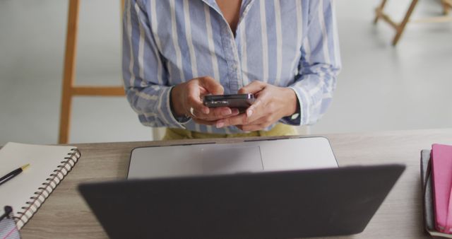 Person text messaging while using laptop at desk in office - Download Free Stock Images Pikwizard.com