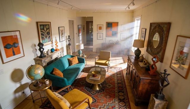 Sunlit midcentury living room featuring teal sofa, mustard chairs and vintage patterned rug