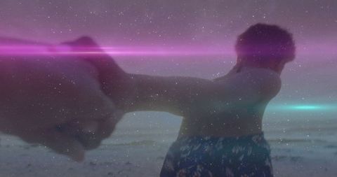 Man Holding Hand on Beach Under Starry Sky at Sunset