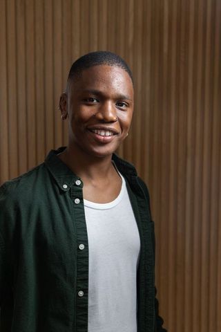 Confident african american man smiling in casual shirt against vertical wood slat backdrop