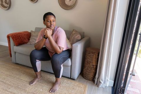 African american woman sitting thoughtful on sofa in cozy athleisure at home
