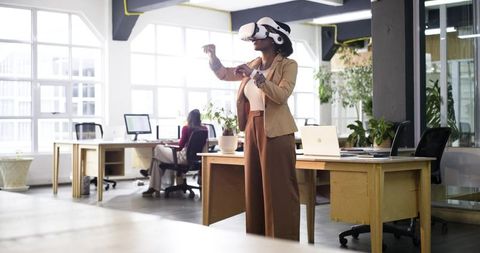 Black businesswoman exploring virtual workspace with vr headset in modern open-plan office