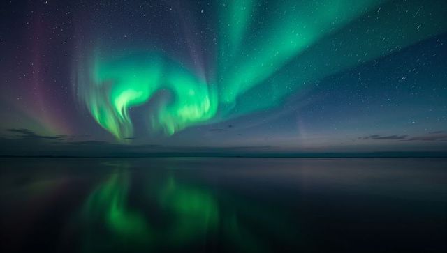Dancing Aurora Borealis Over Calm Sea Reflecting Teal and Green Lights on Night Sky