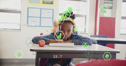 Focused child studying in classroom with futuristic graphic overlays